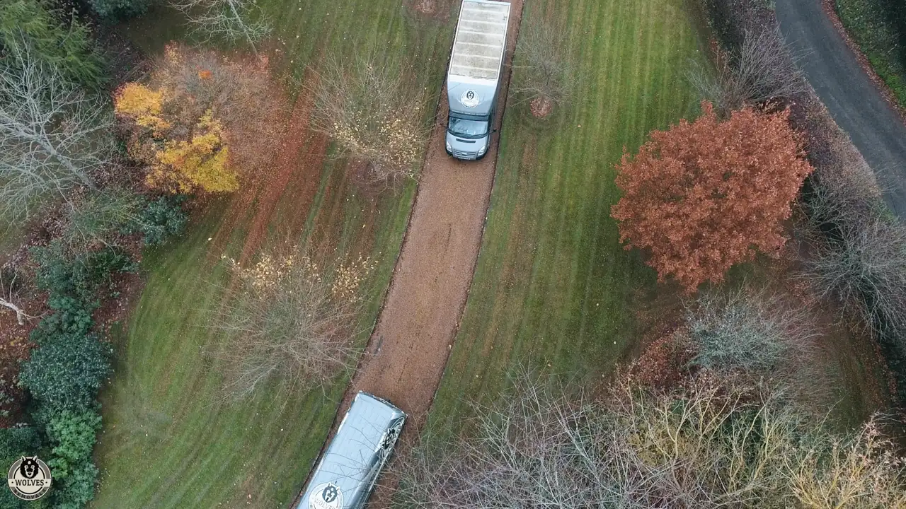 Aerial view of a removal van on a narrow driveway between autumn trees and lawns