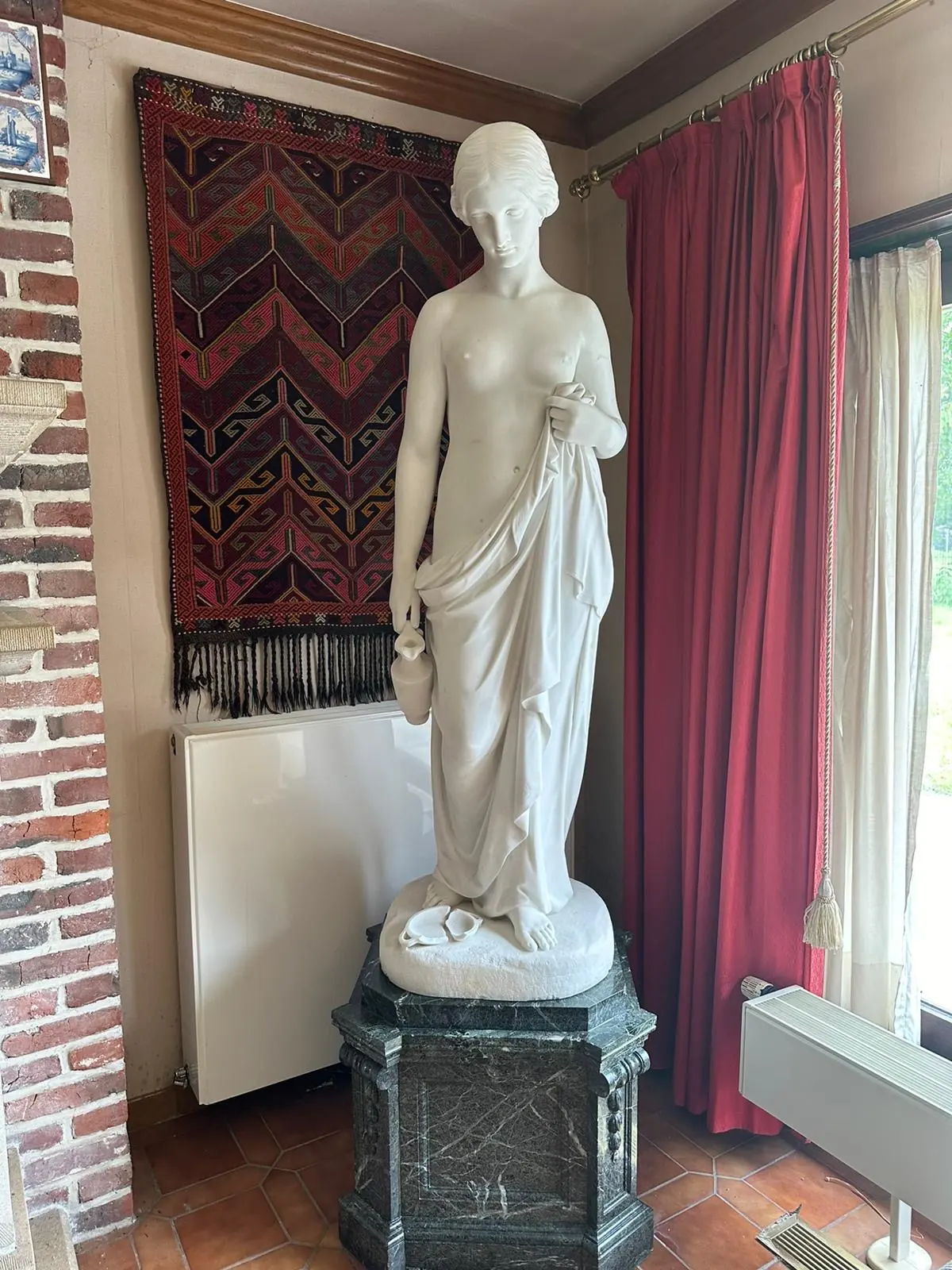 An antique marble statue of a draped female figure on a marble pedestal