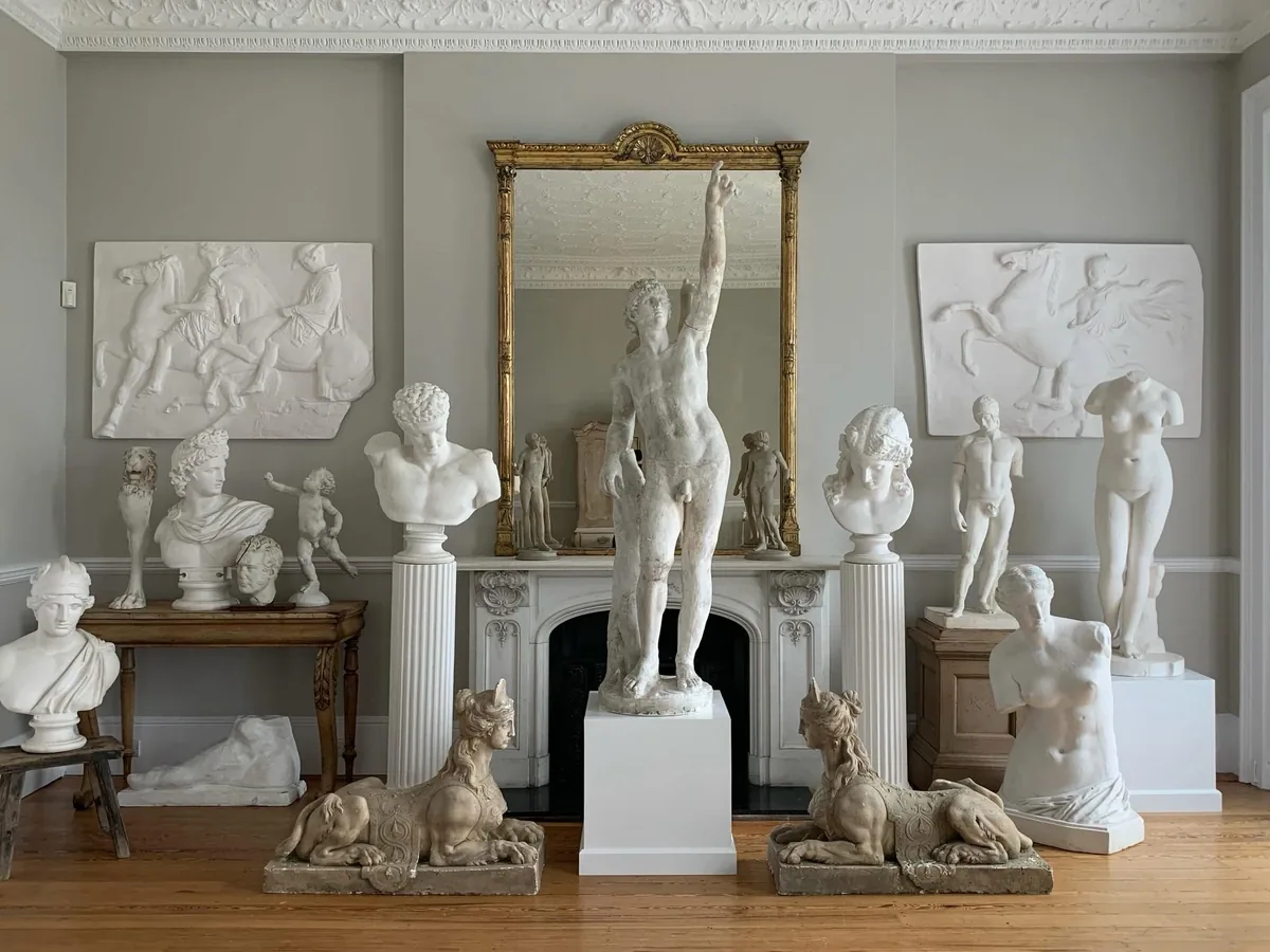 A room filled with classical plaster casts, busts and sculpture arranged before an antiques move in Brighton