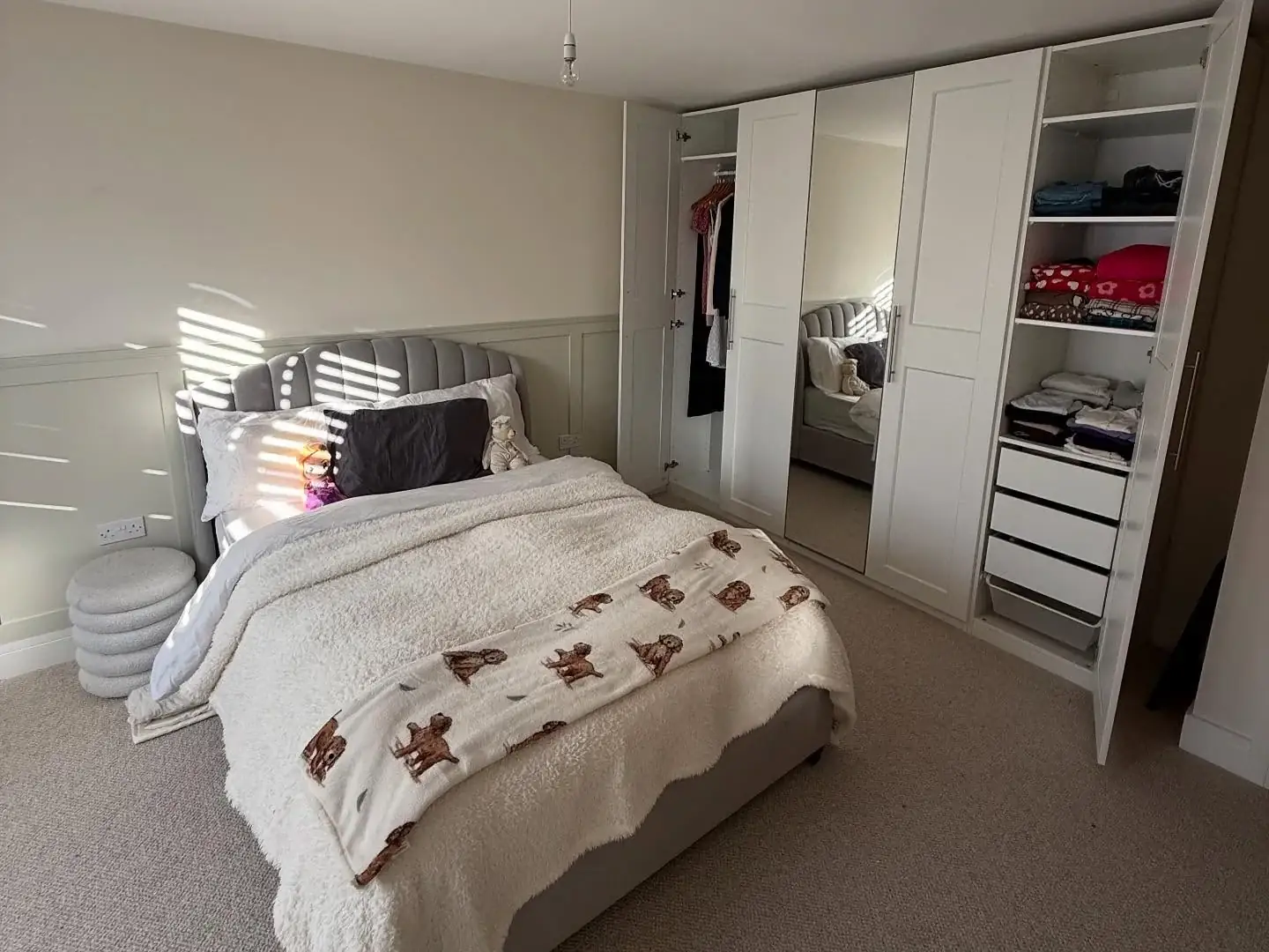 A bedroom after a full unpacking service, with the bed made and fitted wardrobes filled and folded