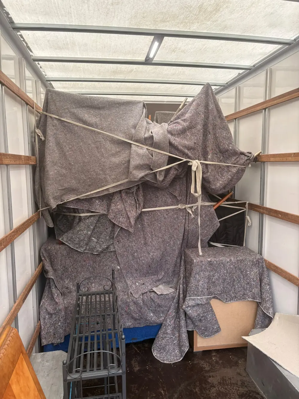 A Luton van stacked high with furniture under grey removal blankets, strapped for the drive to Horsham