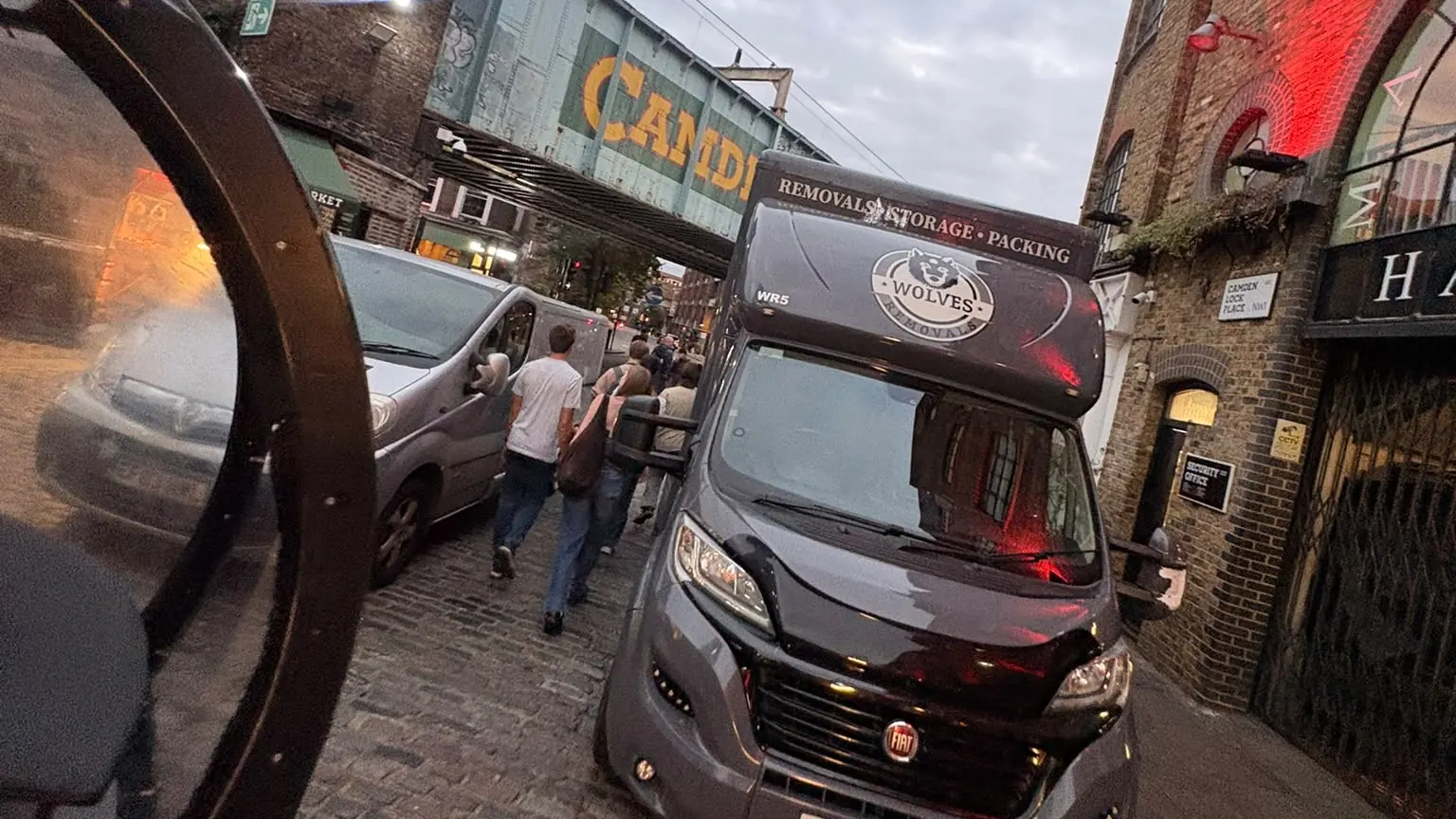 A Wolves Removals lorry in a narrow cobbled lane at Camden Lock Place as shoppers pass