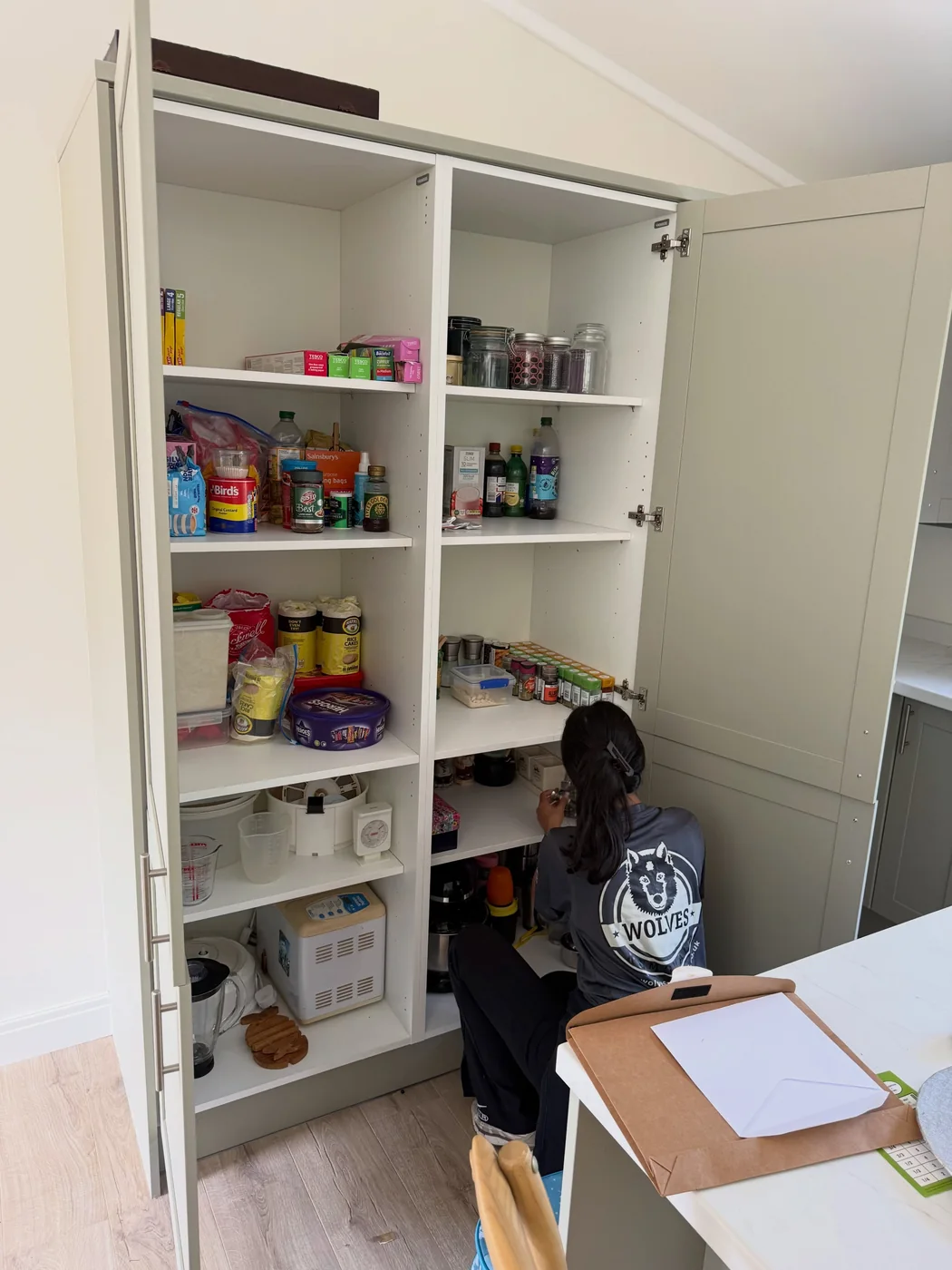 Wolves Removals crew member stocking the shelves of a fitted larder during a full unpack