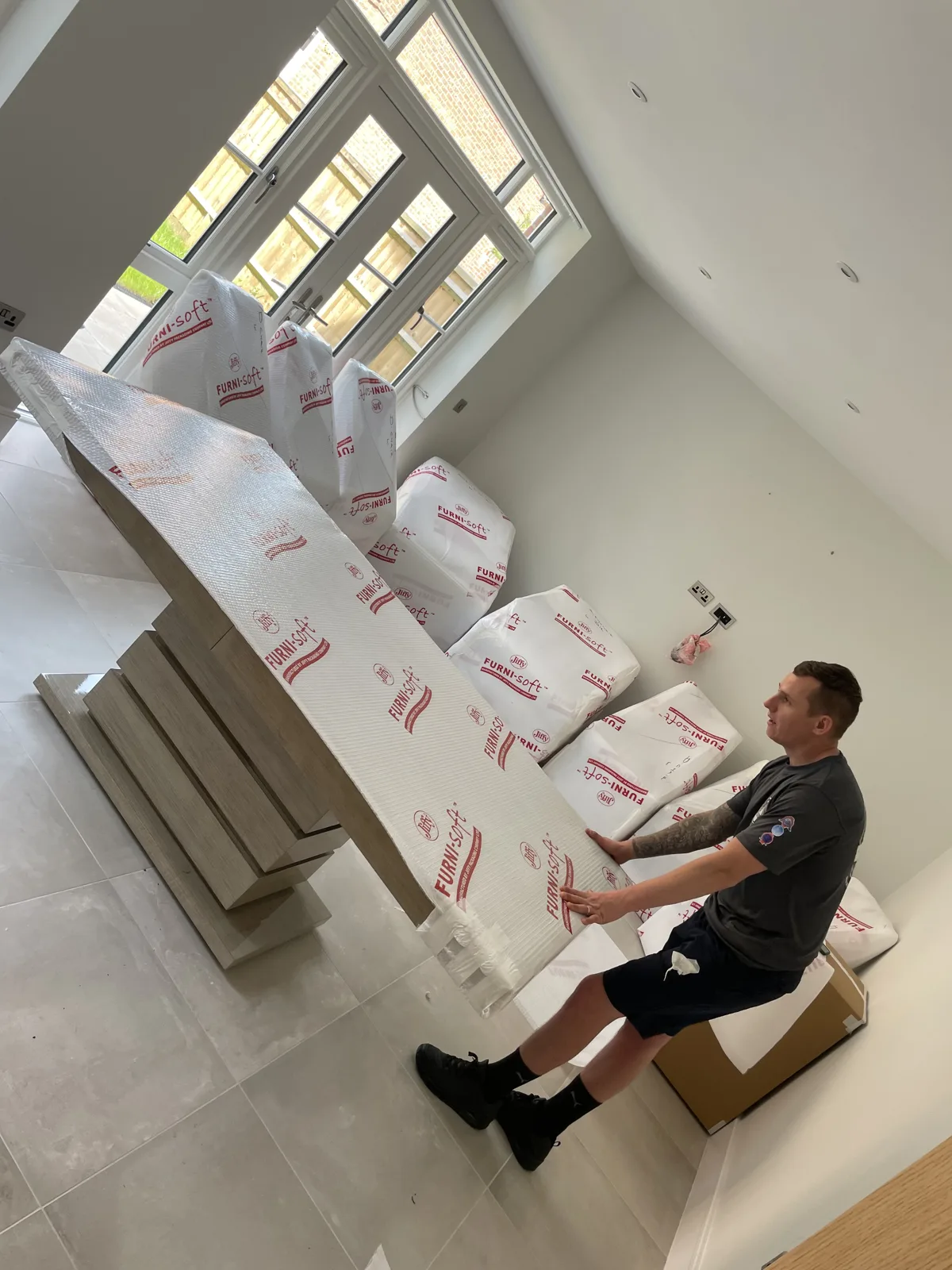 Crew with wrapped furniture in a modern room in Brighton, East Sussex