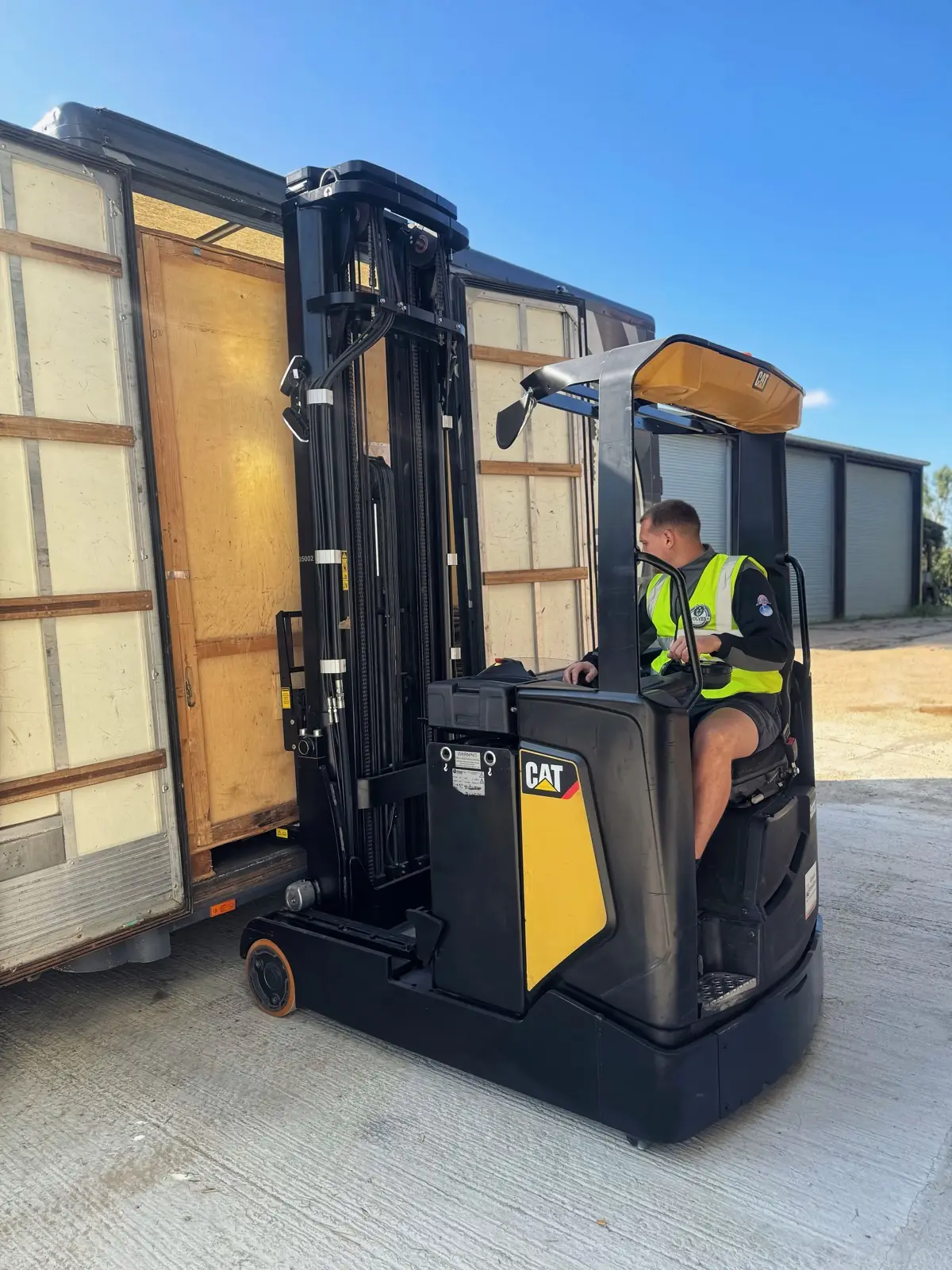 A forklift loading a wooden storage container into a lorry