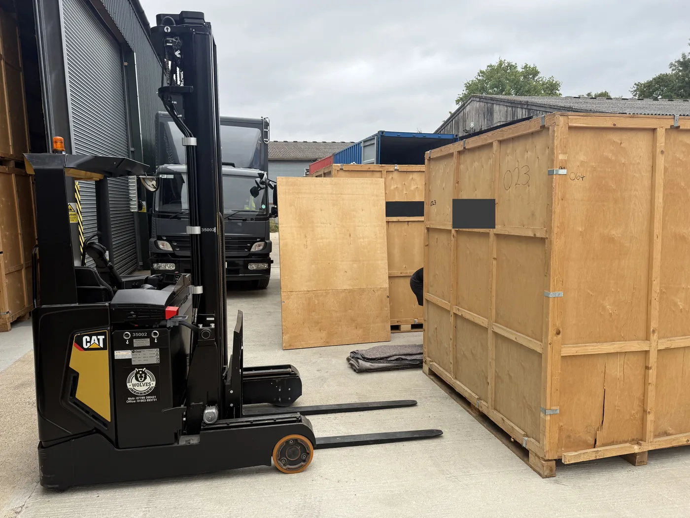 A Wolves Removals forklift positioning a timber storage container in the warehouse yard