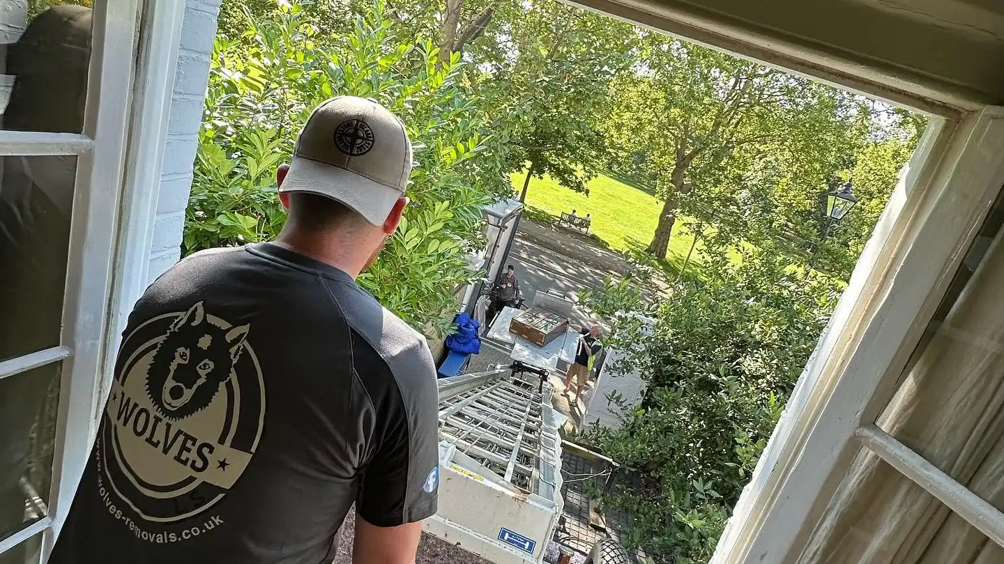 A Wolves Removals crew member at an upper-floor window above an external furniture hoist
