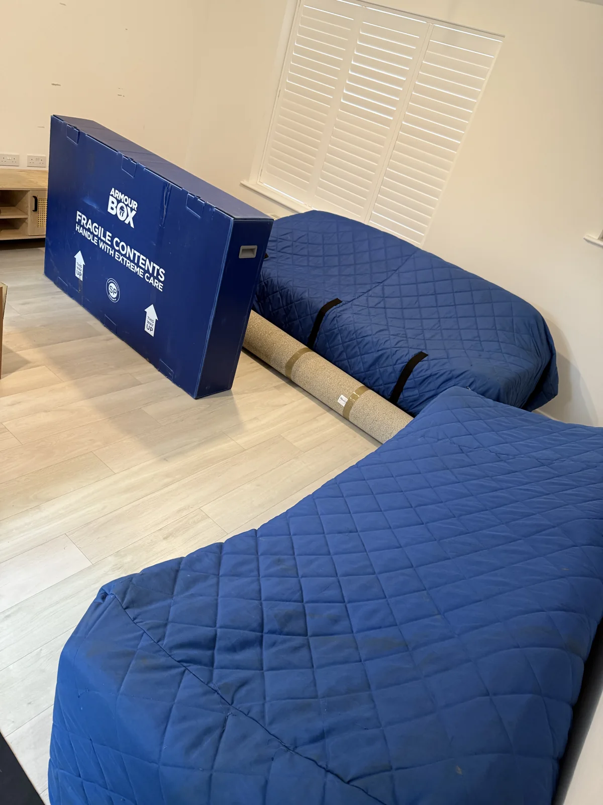 Furniture wrapped in blue quilted moving blankets ready for transport