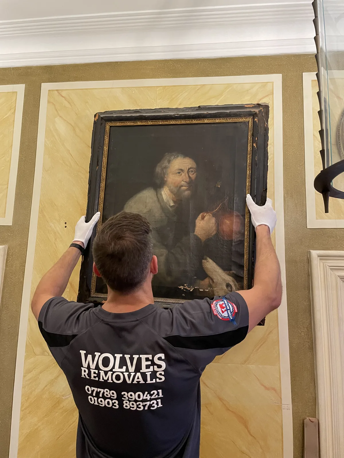 Crew member handling a framed portrait painting