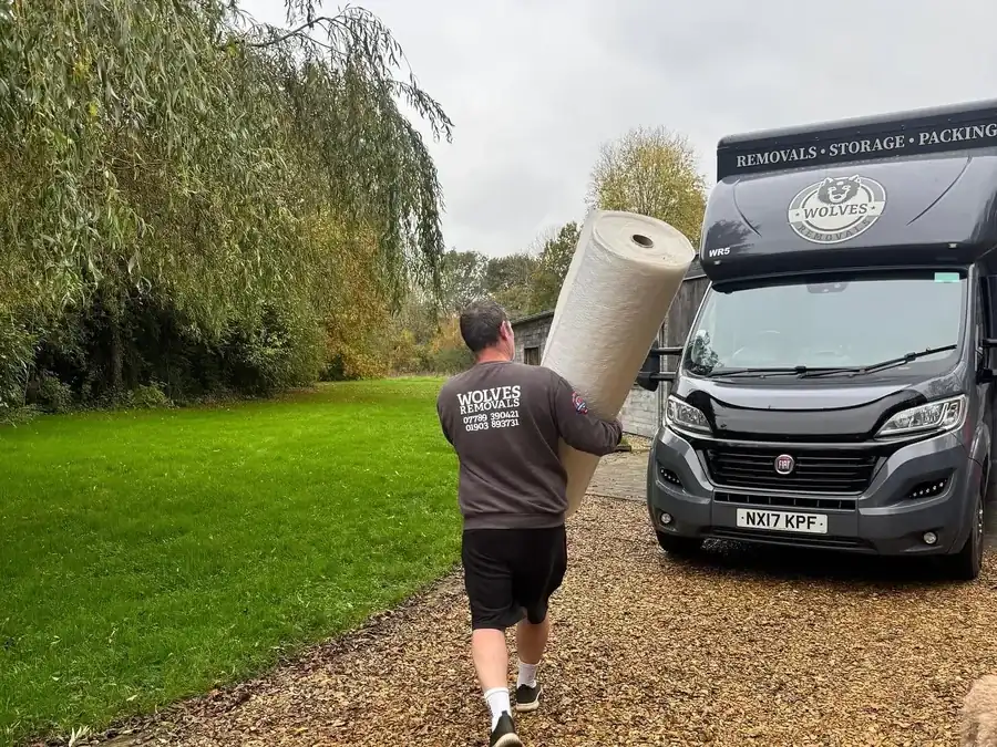 A Wolves Removals crew member carrying a roll of floor protection to the lorry at a property near Horsham
