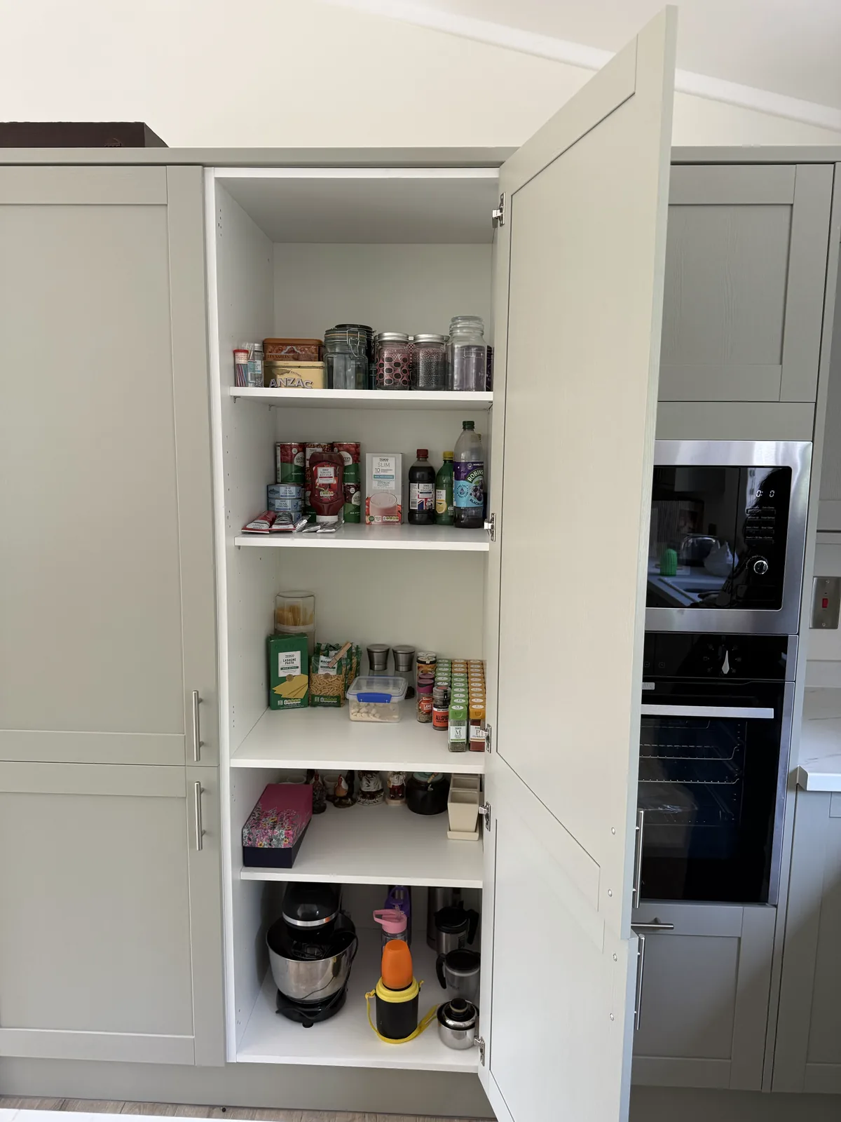 A kitchen larder cupboard unpacked and arranged shelf by shelf after a house move