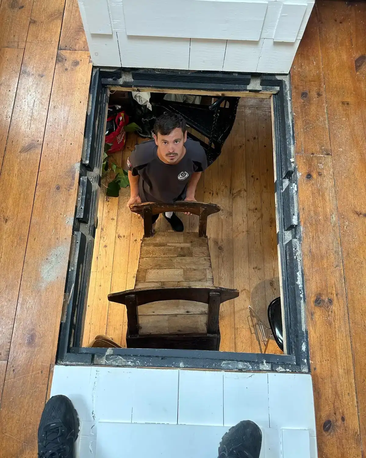 A rectangular lift hatch cut into a boarded timber floor, with a Wolves Removals crew member visible on the floor below