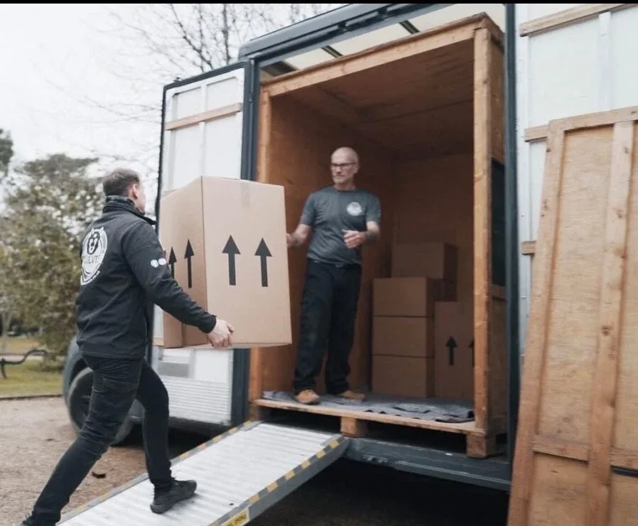 Crew member loading boxes into a van in a rural setting