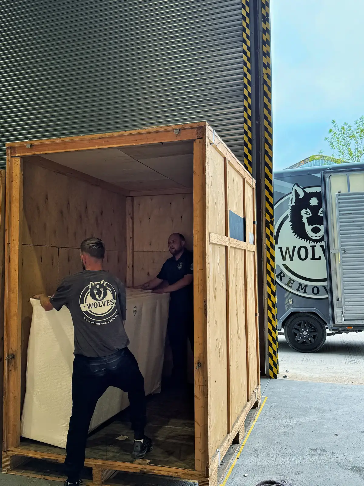 Crew member loading a wrapped item into a wooden storage crate