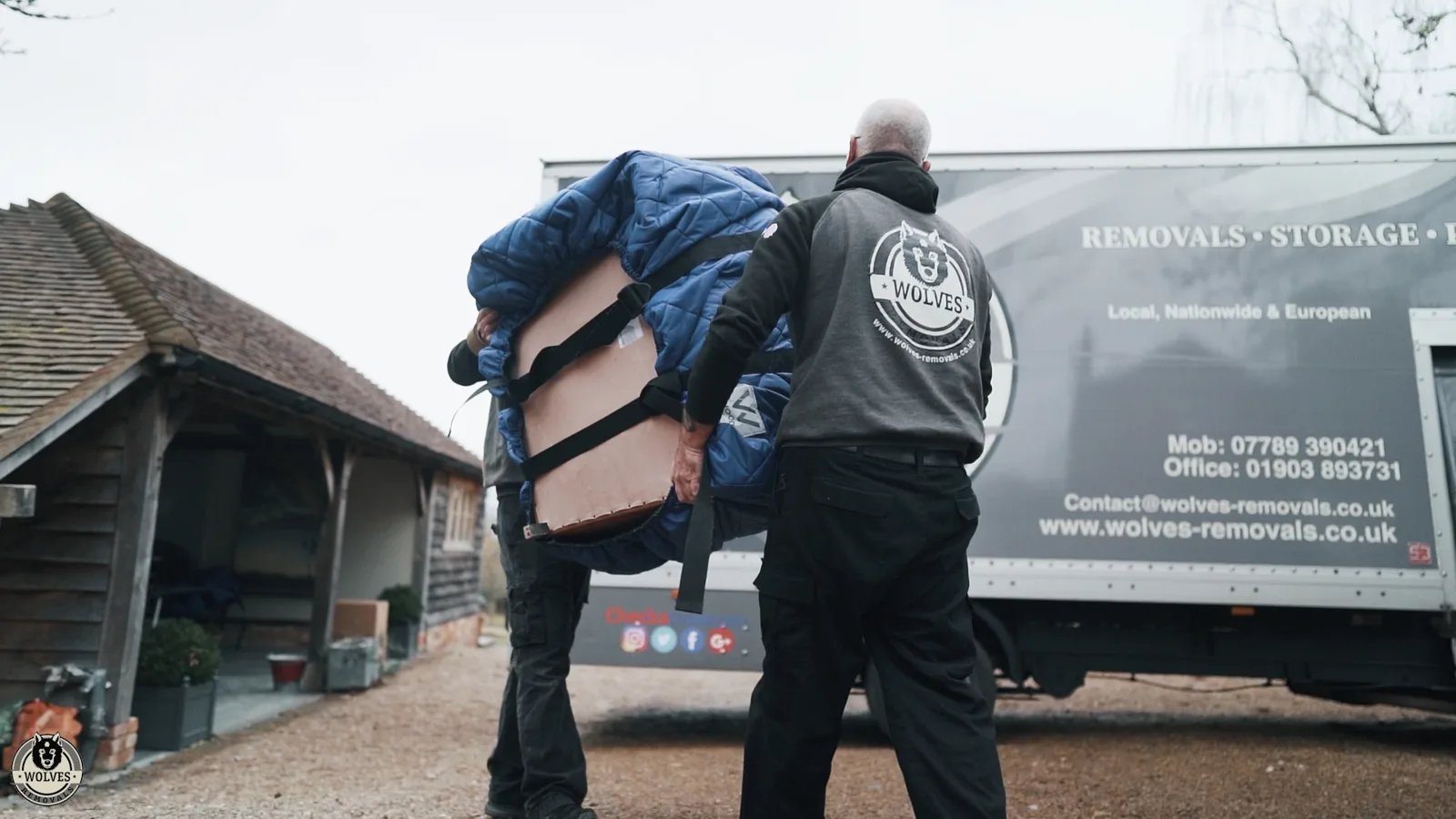 Crew carrying a wrapped item to a removals van