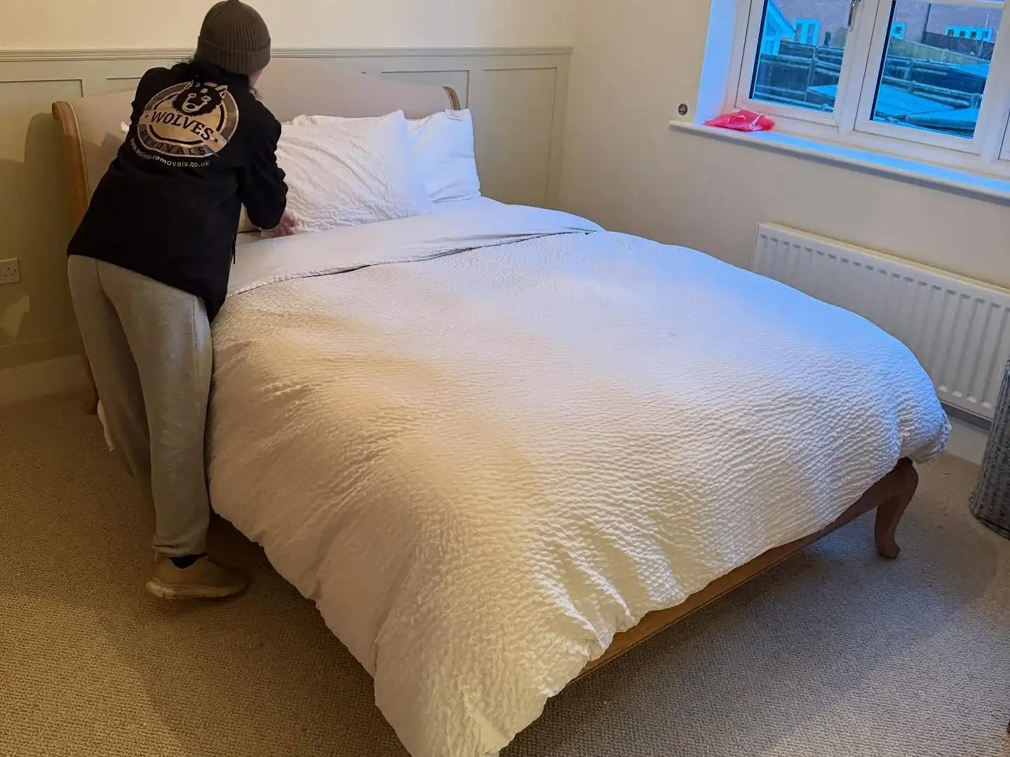A Wolves Removals crew member making up a bed with fresh linen at the end of a house move