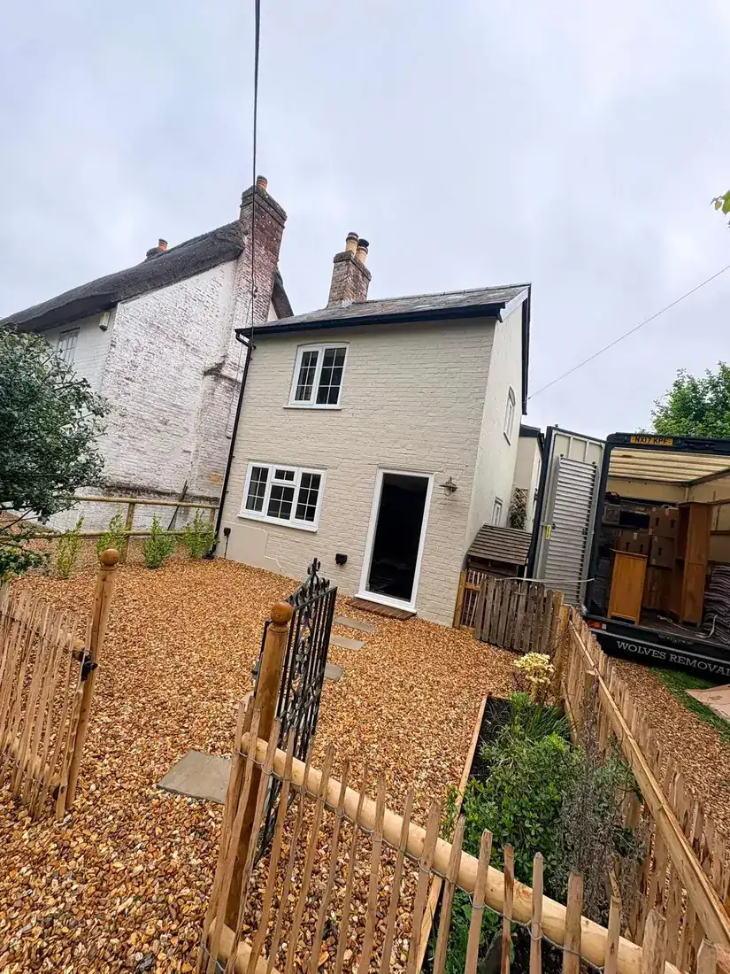 A Wolves Removals lorry loaded with furniture beside a period cottage with a thatched neighbour