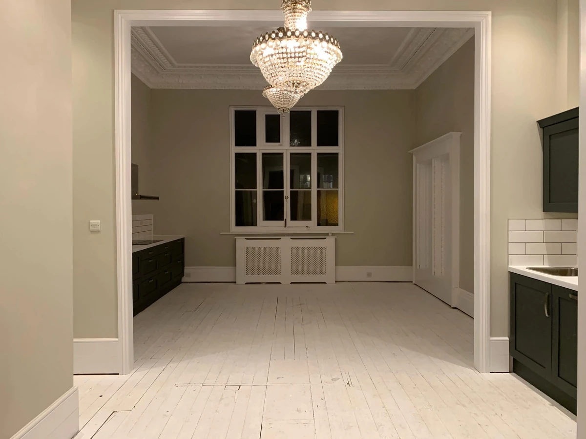 An empty period room with ornate cornicing and a chandelier before an antiques collection was moved in