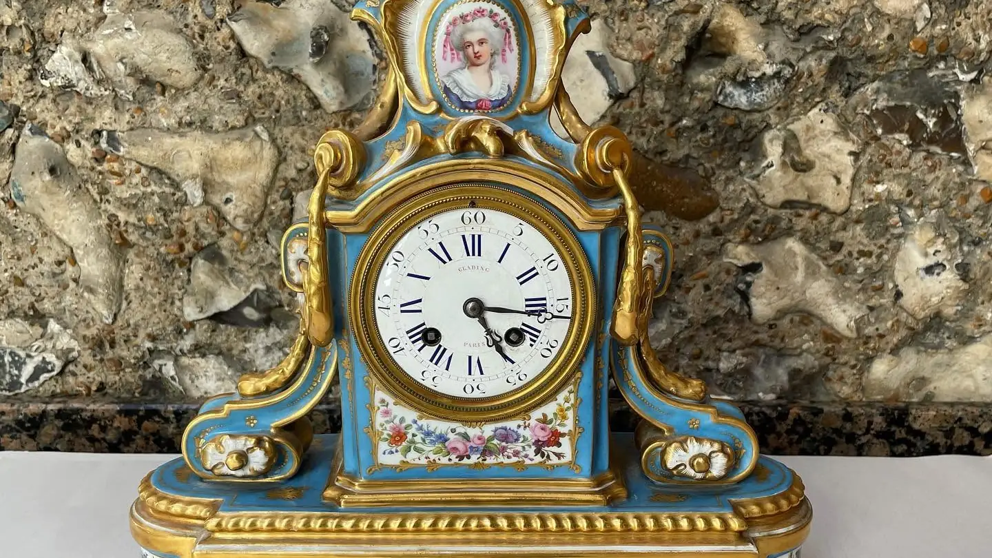 A blue porcelain mantel clock with gilt mounts and painted flower panels