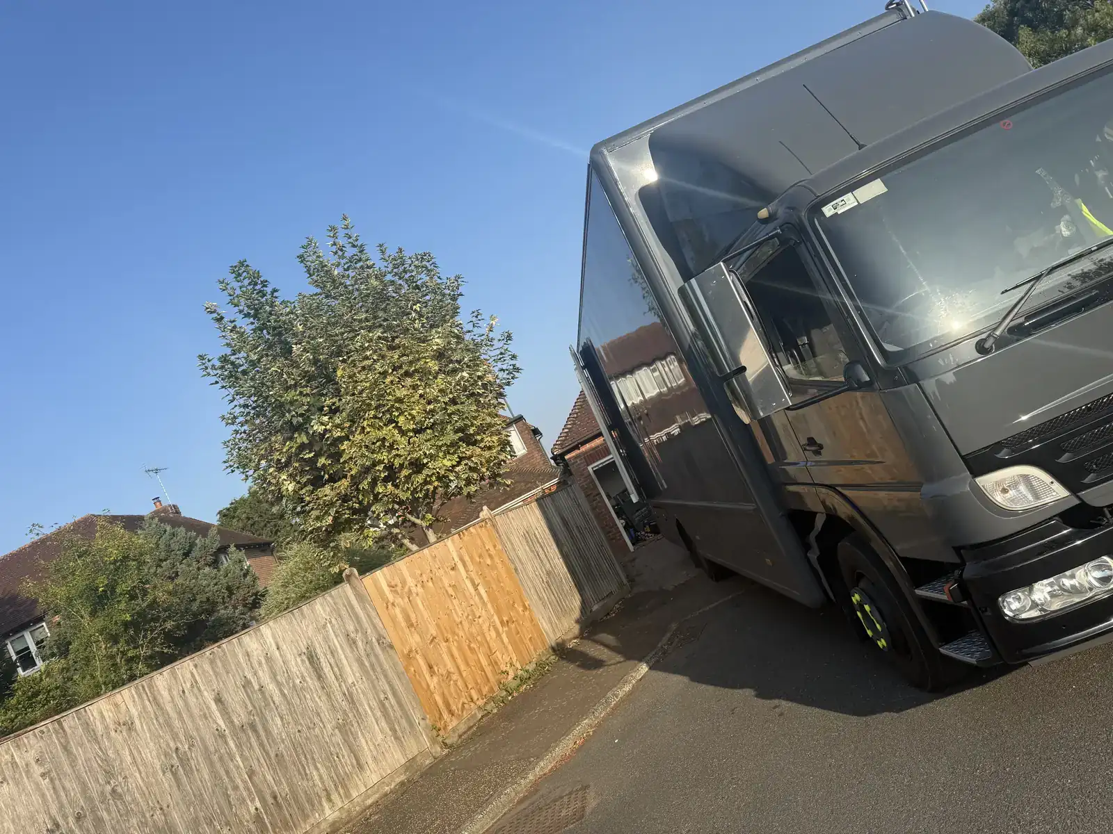 Removal lorry pulled tight against a fence line on a narrow Ashington street