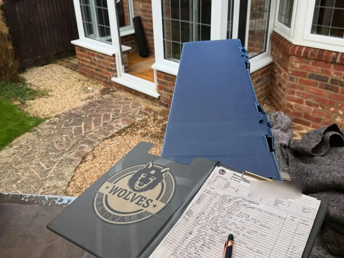 A Wolves Removals clipboard holding a handwritten inventory of a customer's goods in transit, itemised and condition-checked