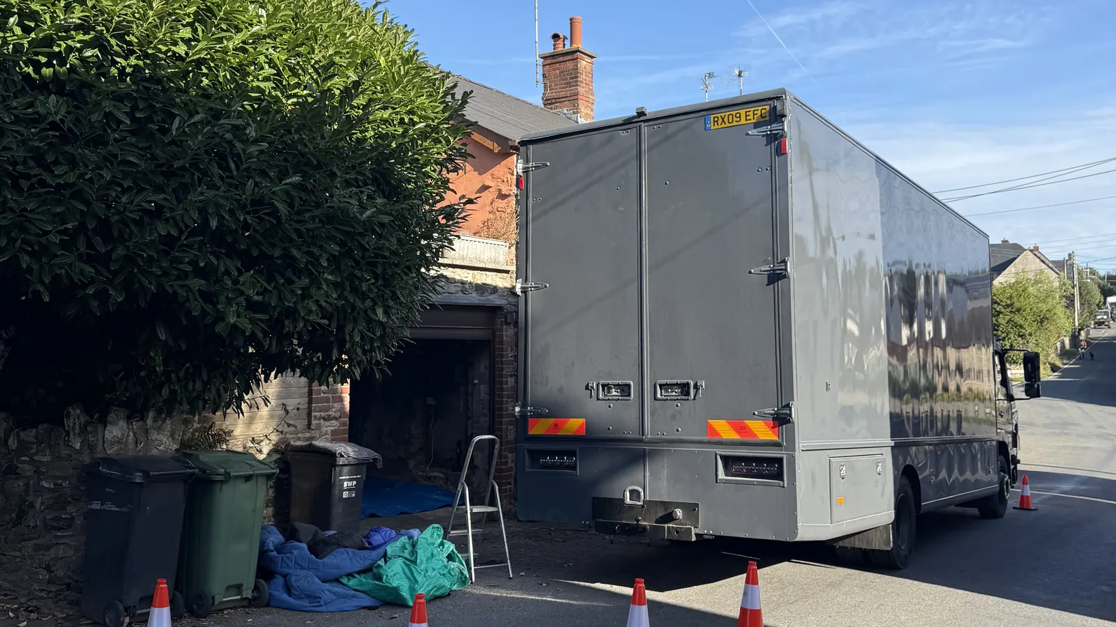 The back of a Wolves Removals lorry open on a Somerset lane with moving blankets laid out