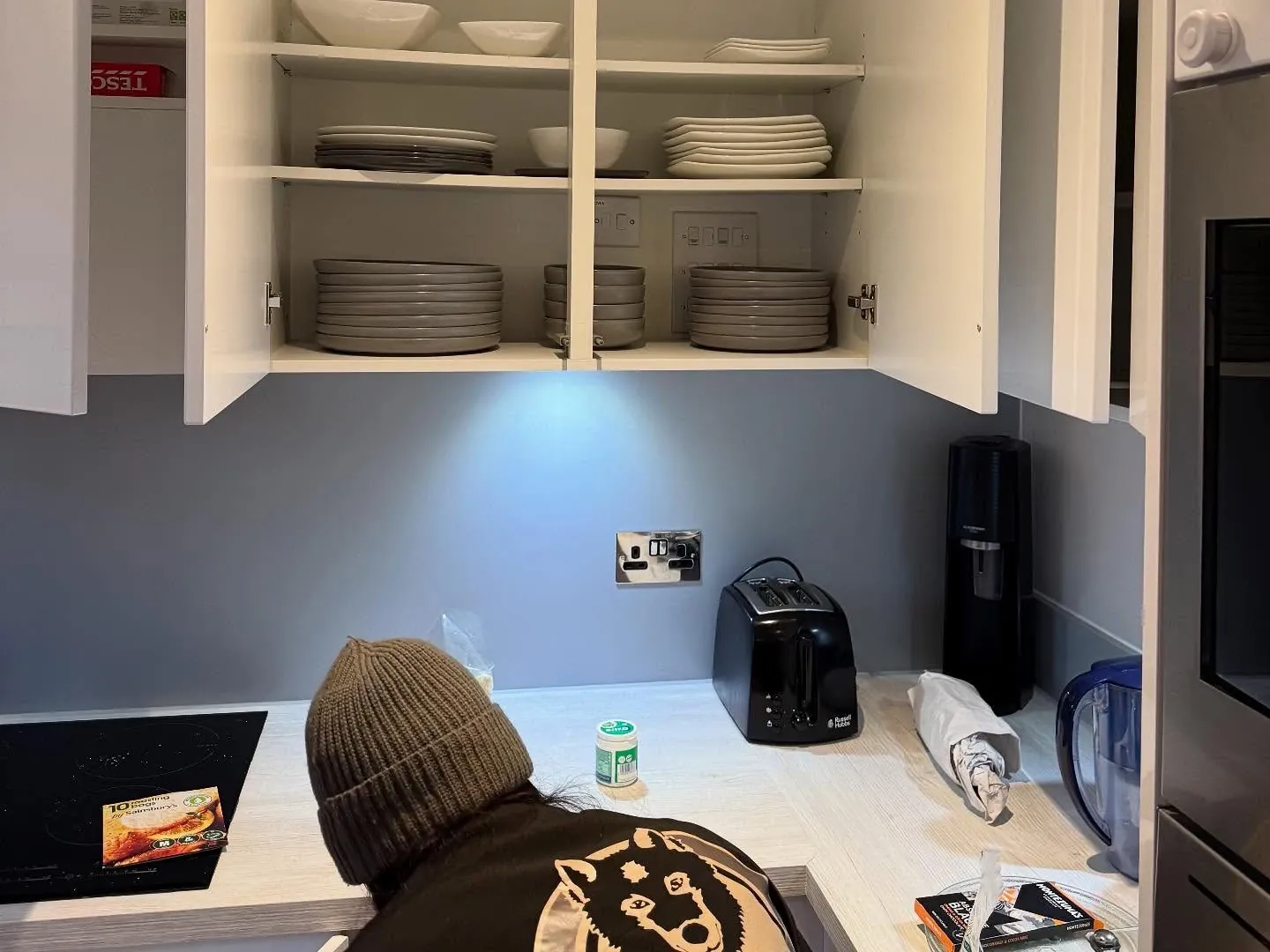 A Wolves Removals crew member loading plates and bowls into kitchen wall cupboards after a house move