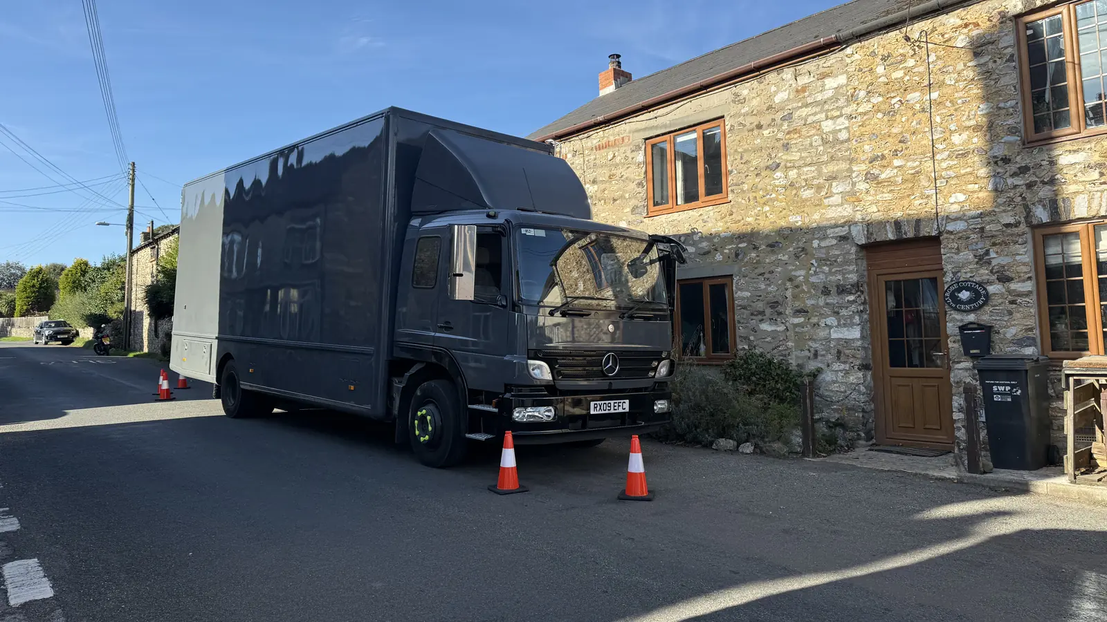 A Wolves Removals lorry outside a stone cottage in Somerset with cones set out at the kerb