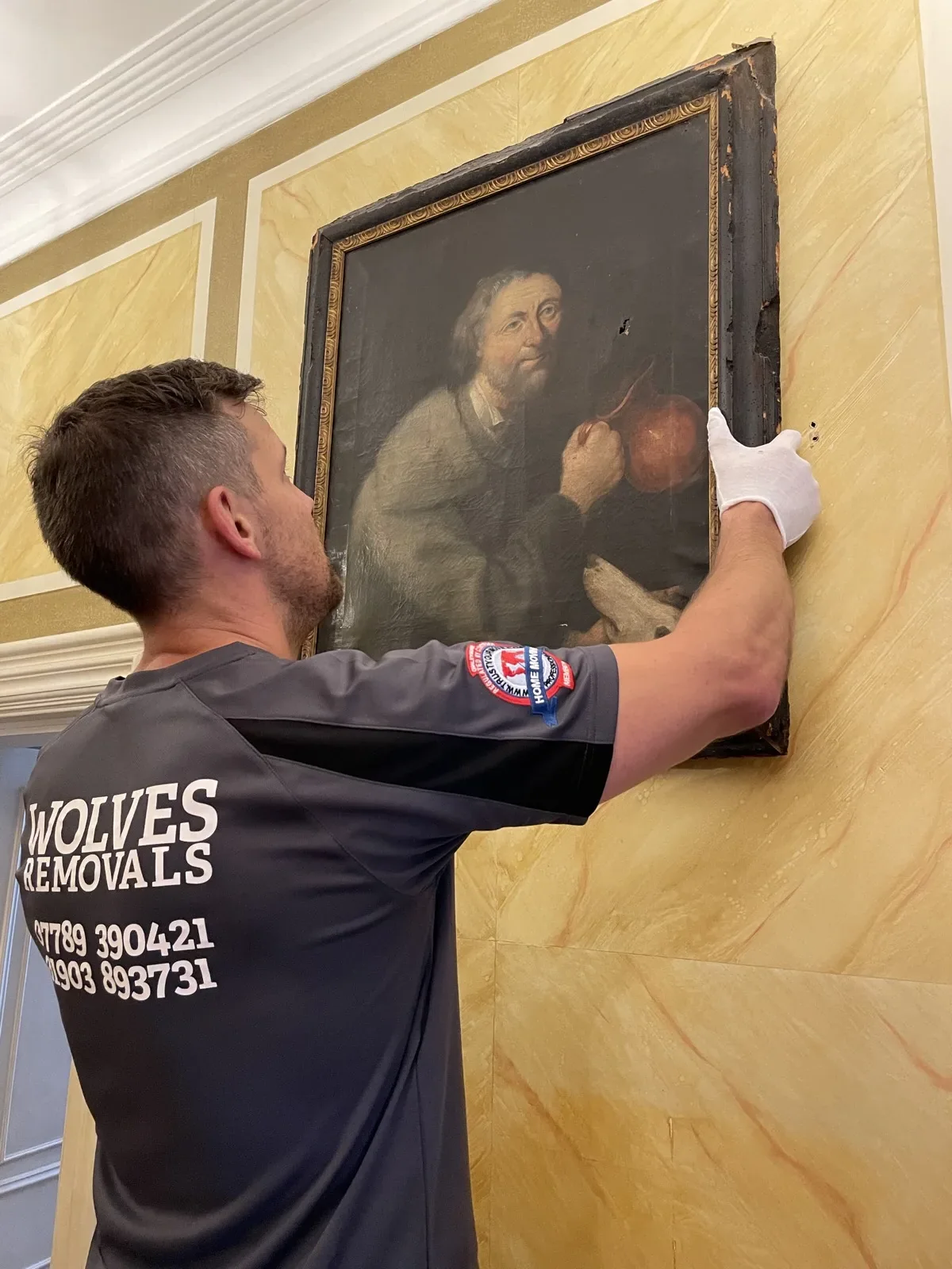 A Wolves Removals mover hanging a framed picture on the wall