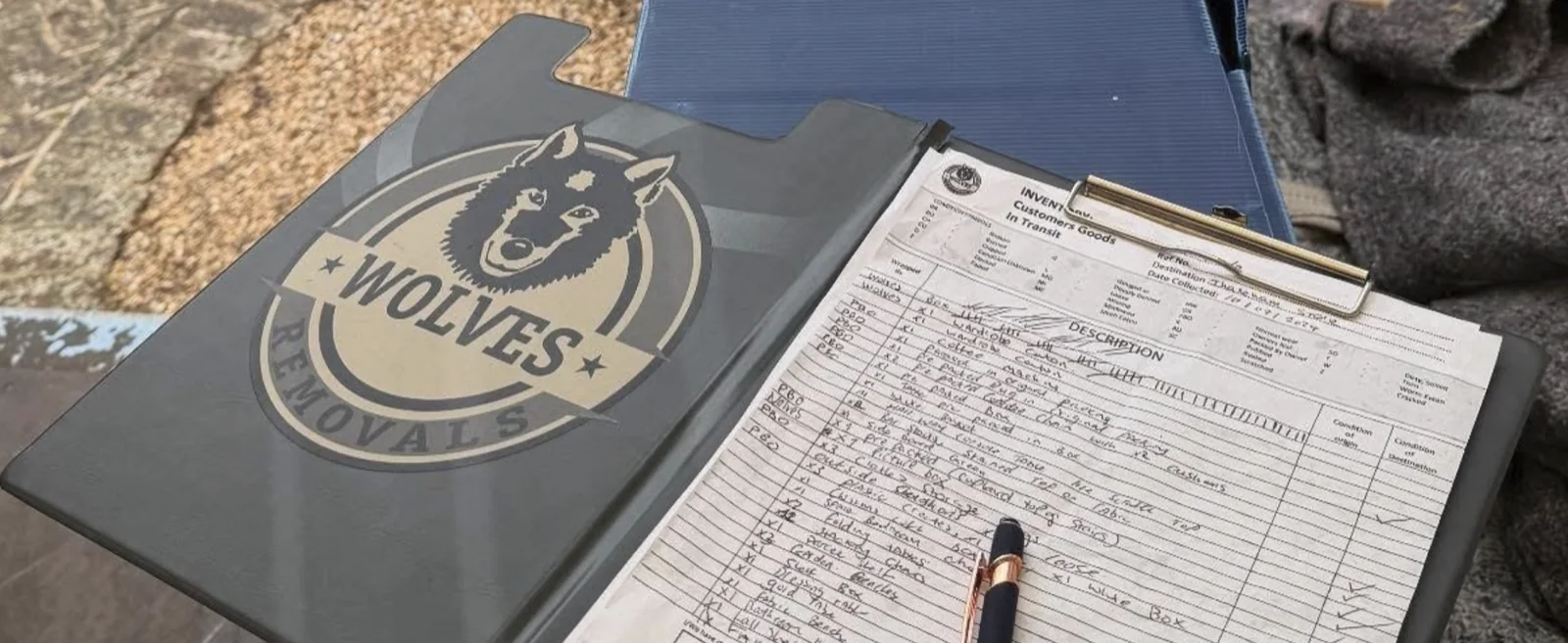 Wolves Removals branded clipboard holding a handwritten inventory sheet with a pen lying across it
