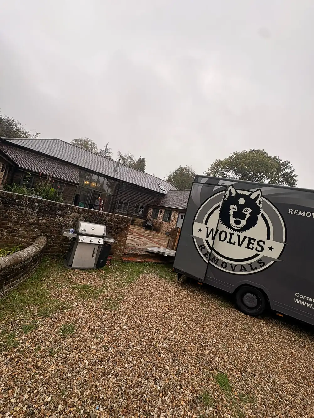 Grey Wolves Removals branded trailer on a gravel drive beside a brick wall and a timber barn conversion