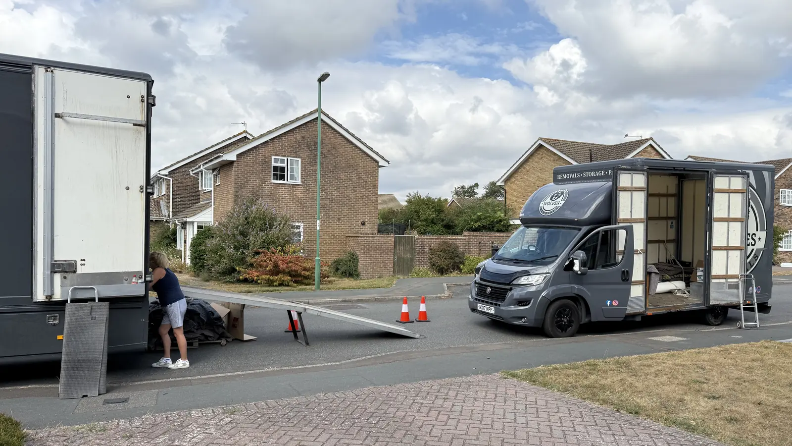 Wolves Removals branded van and lorry at a Storrington delivery, ramp down and cones out