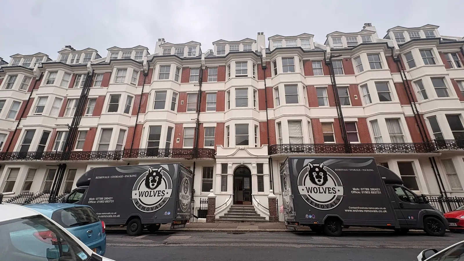 Two Wolves Removals vans parked outside a red-brick period mansion block in Hove