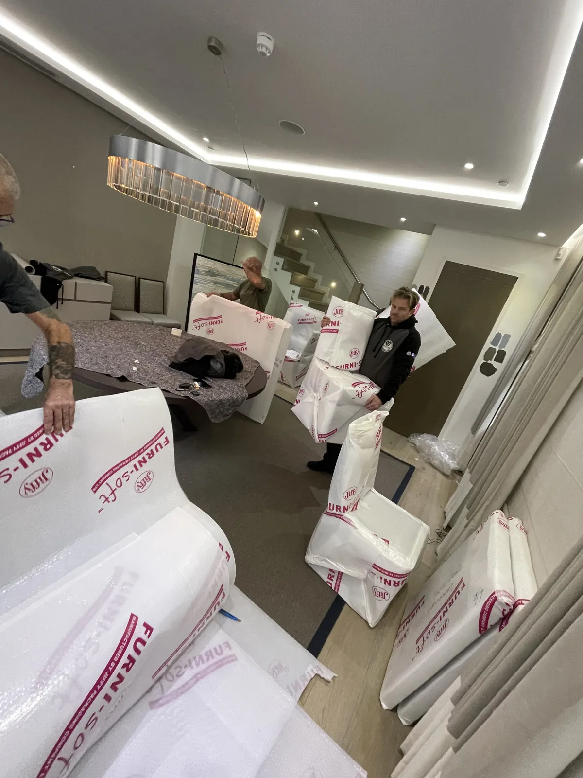 Crew wrapping sofas in protective plastic in a bright room